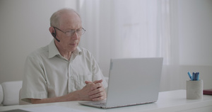 老年男子在笔记本上使用视频电话坐在家中与同事沟通自我16秒视频