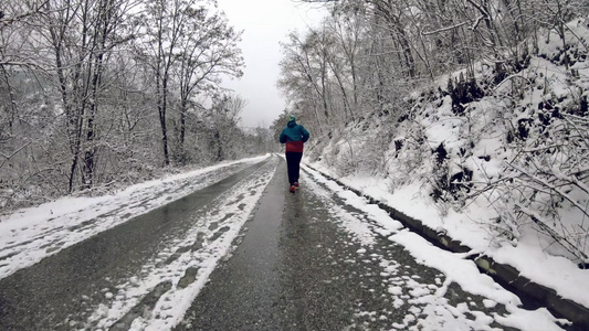 男子冬季在森林中奔跑在农村的雪路上视频