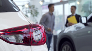 前景的灯光男人购买汽车在经销商在背景背景上9秒视频