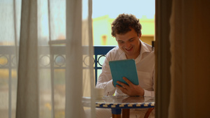 男人在阳台上喝茶和使用用平板电脑25秒视频