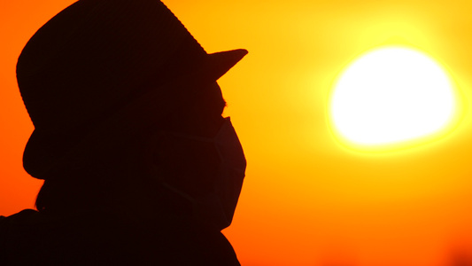 日出日落背景上戴着医用面具的家伙一个戴着美丽景色的视频
