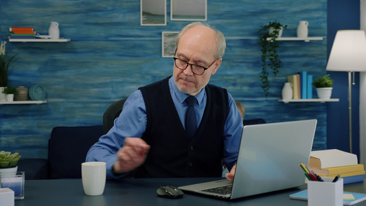 坐在桌桌边喝咖啡看书和打笔记本电脑打字的老年老人视频