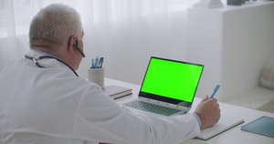 男医生正在办公室在带绿色显示屏的笔记本电脑上18秒视频