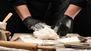 黑乳胶手套大厨在圆木板上的白小麦面粉面团准备披萨面圈19秒视频