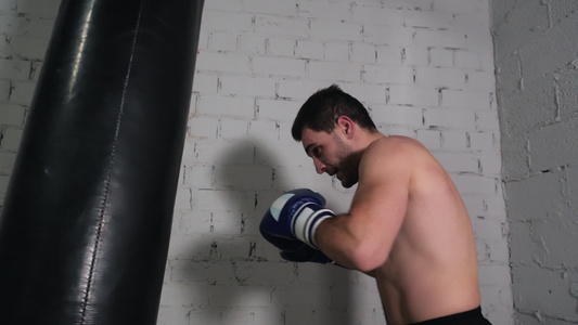 男拳击手在搏击俱乐部用战斗袋训练泰拳练习拳击手在搏击视频