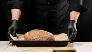 穿黑色制服的厨师在餐桌上放一个金属烘烤盘背着黑底圆8秒视频