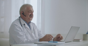 男性治疗师坐在其诊所的办公室里通过视频聊天10秒视频