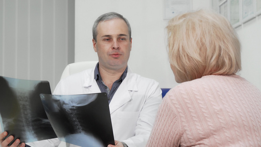 检查一名高级女性患者X光扫描的成年男性大男医生视频