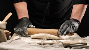 两只男性手戴黑色乳胶手套从白面面粉上用木滚动针缓慢20秒视频