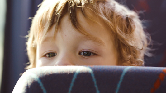 小男孩坐在公车上的座位后面视频