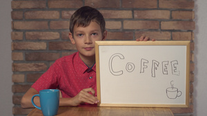 坐在桌边的小孩拿着翻页图在红砖墙上装着咖啡纸11秒视频