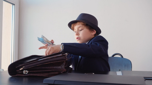 小男孩看起来像企业家把钱藏在公文包里笑声视频