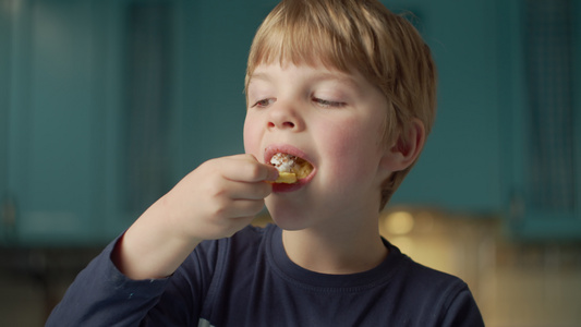 金发学龄前男孩的肖像喜欢吃奶油华夫饼站在蓝色的厨房视频