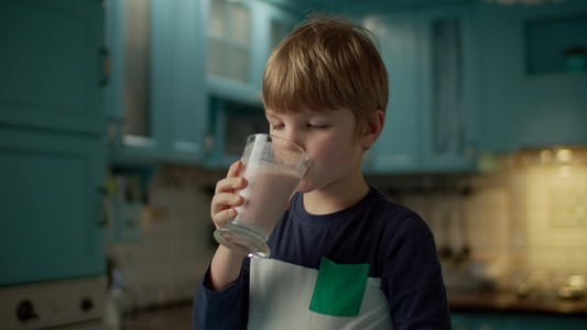 金发学龄前男孩的肖像喜欢在蓝厨房里喝白莓冰淇淋孩子视频