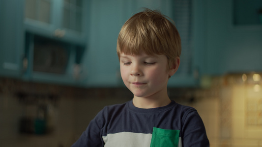 金发学龄前男孩的肖像喜欢吃巧克力棒站在蓝色的厨房孩子视频