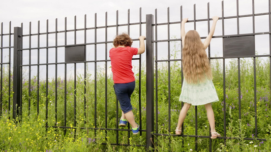 乡村的男女儿童爬上铁栅栏暑假时在村里玩得开心的小孩视频