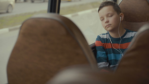 一名男孩乘公车穿过城市的近距离拍摄他收听音乐14秒视频