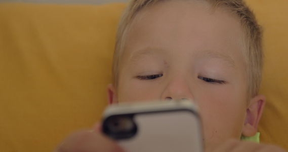 在智能手机上玩游戏的小男孩近距离拍摄视频