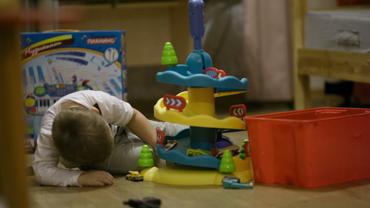 小男孩玩一个塑料车库的玩具小男孩视频
