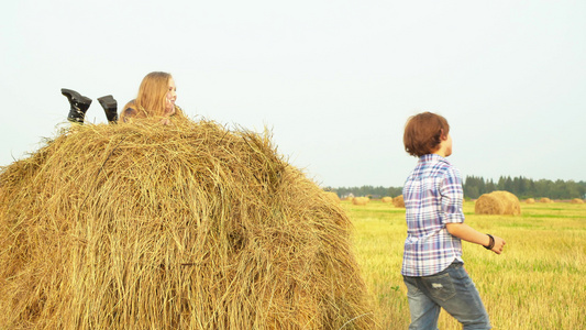 男孩站在田地上女孩躺在干草堆上视频