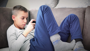 男孩坐在沙发上用智能手机玩游戏20秒视频