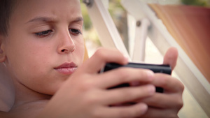 暑假时躺在海滩床上男孩在智能手机上玩游戏18秒视频