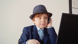 小男孩在商务办公室用手机前面的笔记本电脑打电话装大人18秒视频