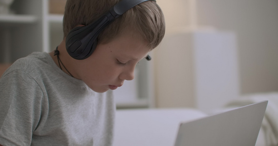小男孩在家里戴耳机的肖像画孩子在书本上画画听音乐视频