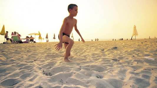 小男孩在海滩上奔跑在日落时翻转视频