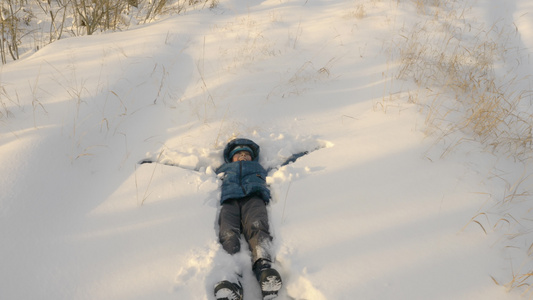 小孩让雪天使躺在雪地上视频