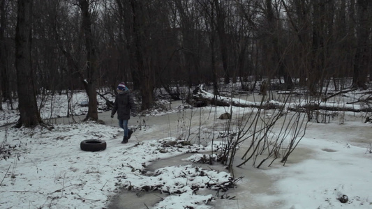 少年从冬季公园的路上取走废旧轮胎视频