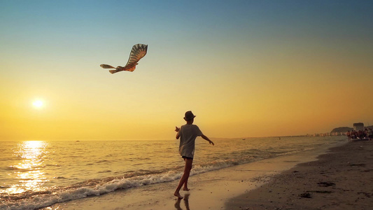 跟着一个年轻男孩带着飞风筝跑在空海滩上在背景的夏天视频