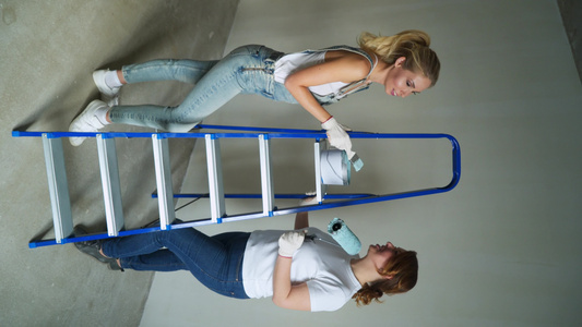 两名女工用滚滚机在墙壁上涂漆以视频