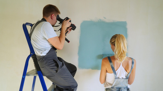 女工用桶装滚滚筒在公寓里油漆墙壁或视频