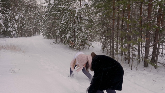 母亲和女儿在冬季森林中玩雪斗慢动的冬林视频
