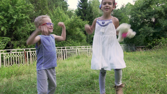 两个小孩蹦蹦跳跳年轻可爱粗心的孩子在后院玩耍视频