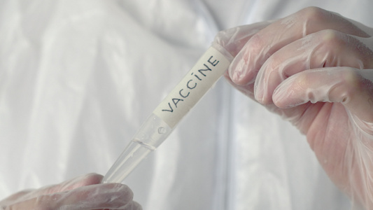 学家在科学实验室里拿着带有疫苗铭文的管子医学实验室视频