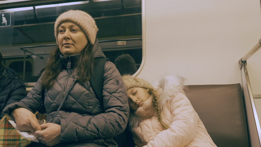 在现代城市的地铁列车中驾车的疲累的母亲和睡着的女儿视频