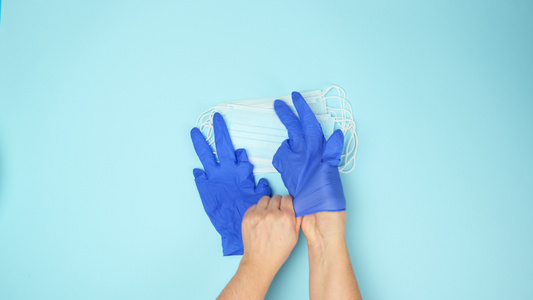 两只女手戴上蓝色乳胶手套戴上一次性医用口罩俯视流行病视频