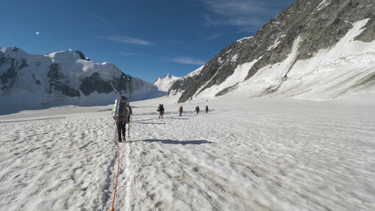 一群带背包的登山者被捆绑在一起在阳光明媚的日子在雪山视频