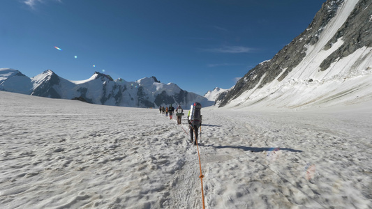 一群有背包的登山者被捆绑在一起在雪山中的冰川上行走视频