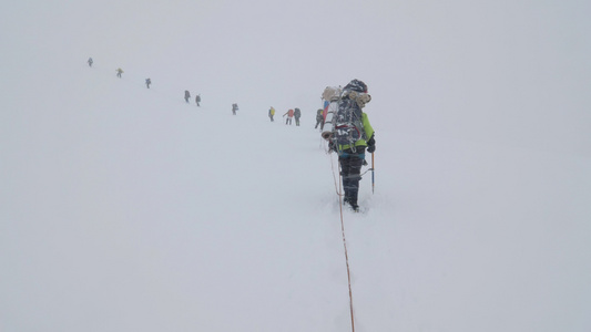一群带有背包的登山者被捆绑在一起在雪崩下雪山中的冰川视频