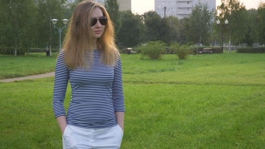 戴太阳镜长发的年轻女子在公园里走来走去视频