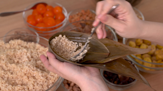 做粽子粽子—家人准备在家里的木桌上把一堆中餐包起来视频