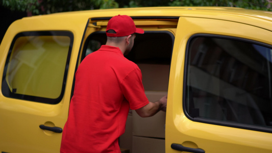 送货员从黄色汽车里拿出包裹视频
