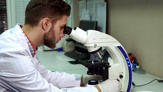 男人通过实验室的显微镜看人视频