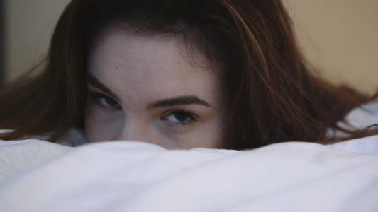 青年妇女的眼睛看着躺在床上和摇头的照相机视频
