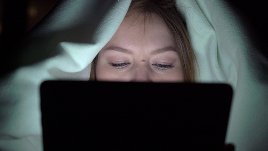 年轻女性睡前在床上使用平板药即手机上瘾者的概念视频