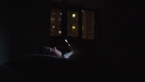 年轻女子在晚上睡觉前在床上使用手机11秒视频