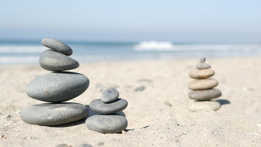 在海洋海滩上平衡岩石在海浪中堆叠石头沙滩上的碎石金字塔视频